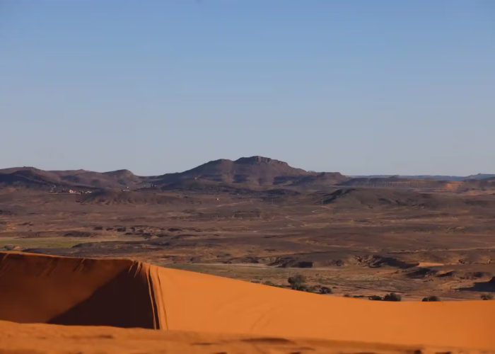 Panoramic view from the top Erg Chabbi Sand dunes show a good contrast of the black rocky desert and the orangey color of the sand - Morocco travel package - Morocco tour package - Morocco holiday - Morocco vacations - Morocco vacation packages - Tangier excursions