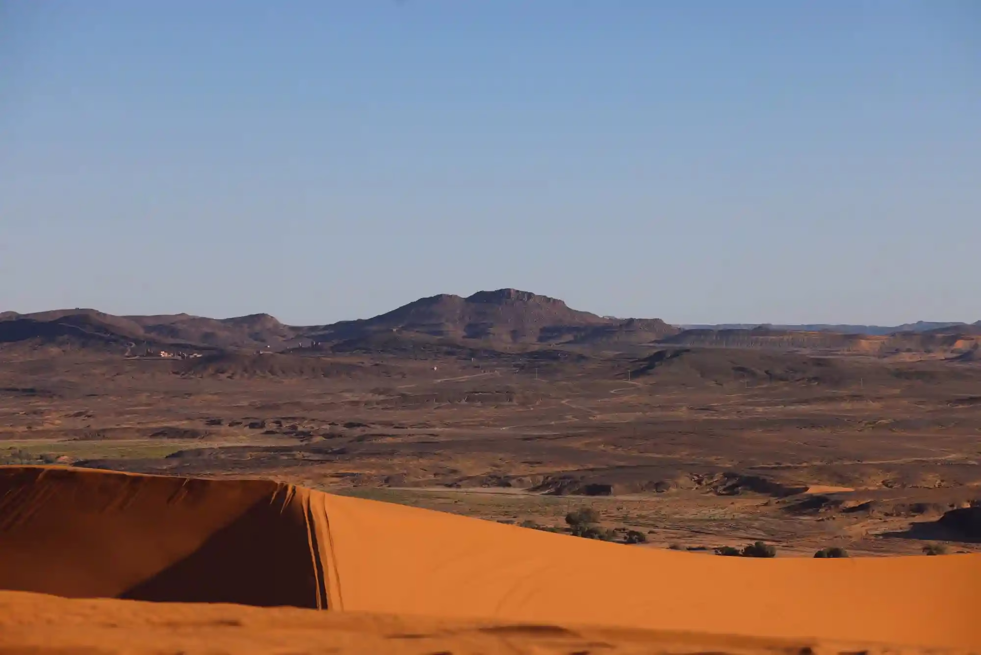 Panoramic view from the top Erg Chabbi Sand dunes show a good contrast of the black rocky desert and the orangey color of the sand - Morocco travel package - Morocco tour package - Morocco holiday - Morocco vacations - Morocco vacation packages - Tangier excursions / Viaggio di 4 giorni da Tangeri - Vacanzi Da Tangeri