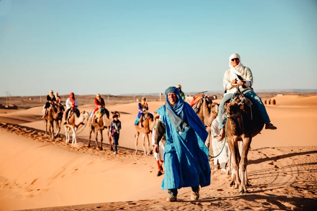 Carovana di cammelli con guide berbere tra le dune di Merzouga