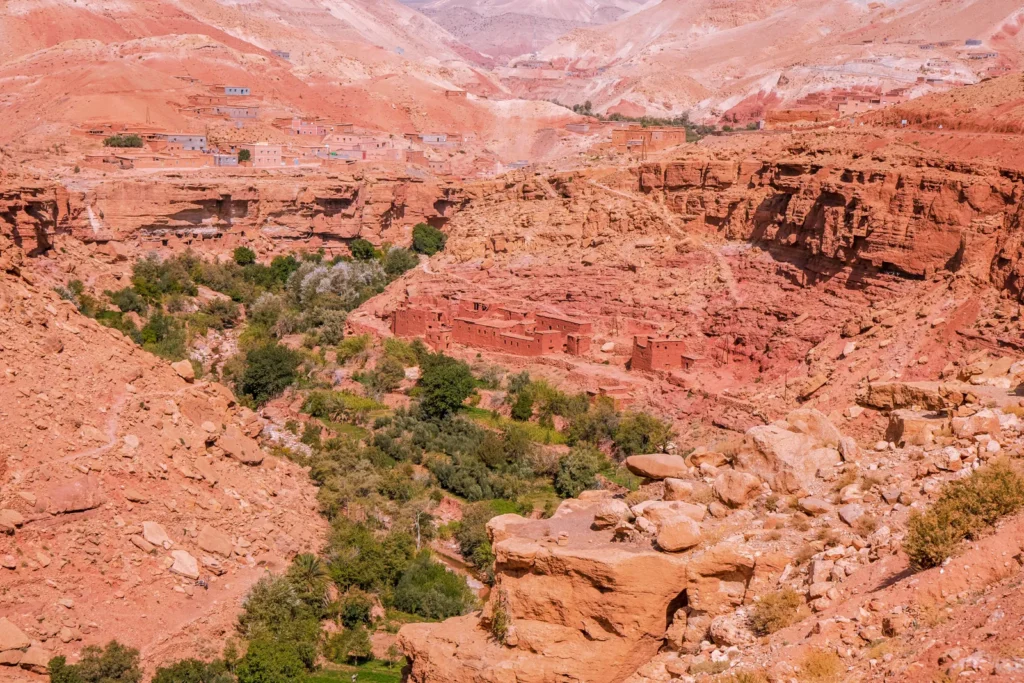 Red cliffs and green valley floor on the road through southern Morocco
